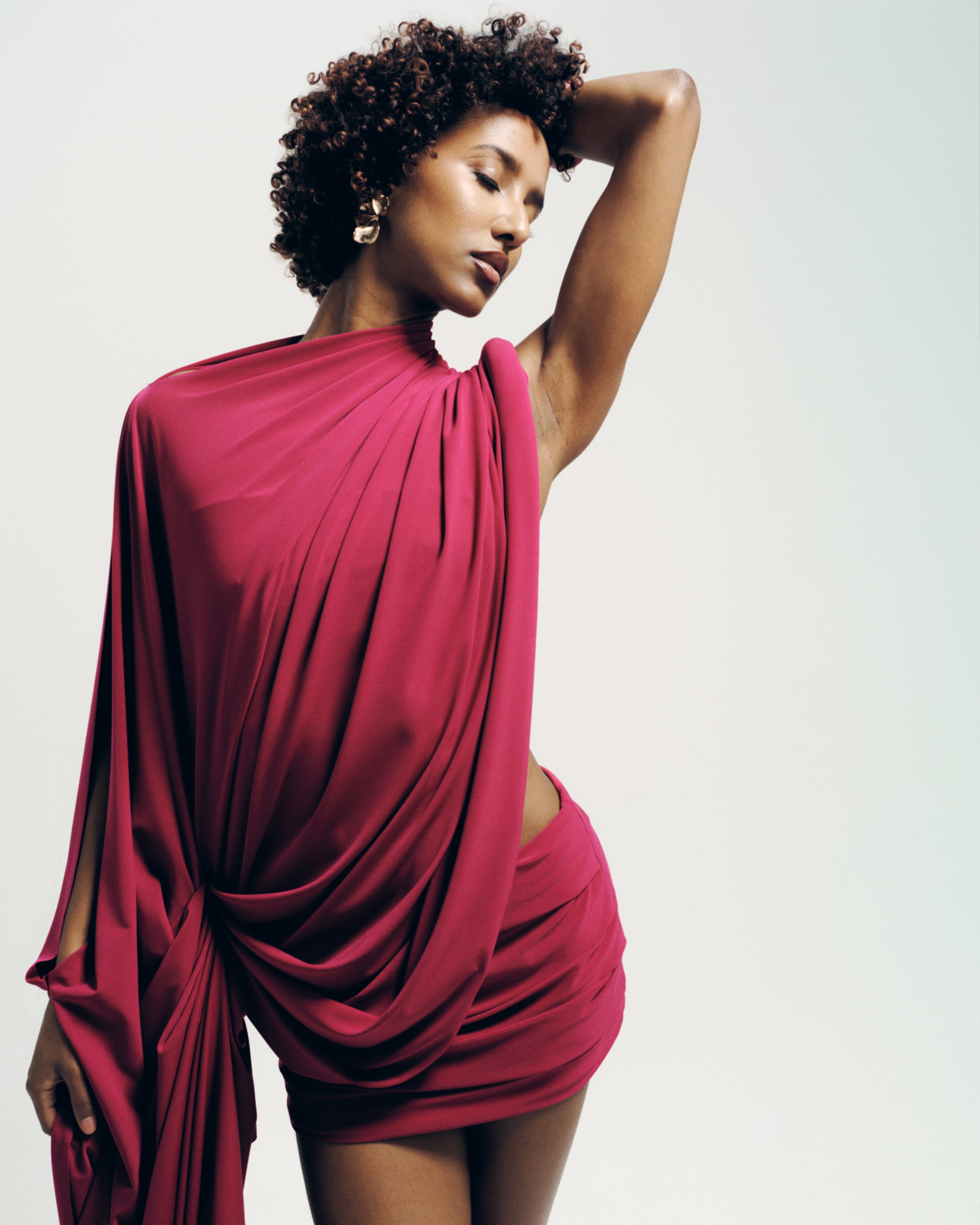 Model wearing the Signature Draped Top in raspberry, featuring a draped high neckline and flowing silhouette. Made-to-order in the UK.
