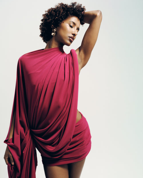 Model wearing the Signature Draped Top in raspberry, featuring a draped high neckline and flowing silhouette. Made-to-order in the UK.